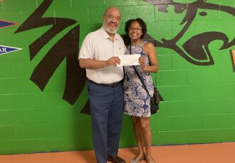 Jon Mangana, CEO ACDC Baltimore presents check to Crystal Bazemore, Asst. Principal of NAF Middle School to sponsor a field trip for her students